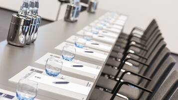 Una mesa de conferencias con botellas de agua, vasos y bolígrafos.