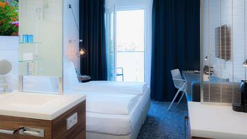 Ein Hotelzimmer mit Bett, Schreibtisch, Stuhl, Badezimmer mit Spiegel und einem Fenster mit Vorhängen.