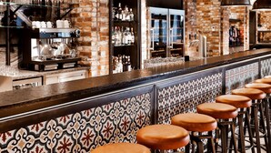 A bar area with a long counter, multiple stools, and hanging lights. - Dorint Hotel Düren (Dueren)