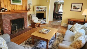 A cozy living room with a fireplace, a television, and a bookshelf.