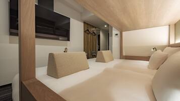 Ein modernes Hotelzimmer mit einem Holzkopfteil, einem großen Bett mit beigen Kissen, einem kleinen Nachttisch und einem Spiegel.
