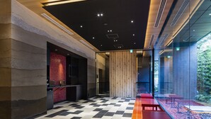 A modern hotel lobby with a checkered floor, a reception desk, and a seating area with red benches. - the b asakusa (Tokyo)