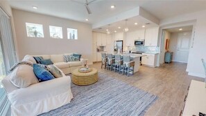 A modern living room with a sofa, a round coffee table, and a dining area with chairs and a table.