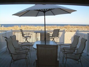 Una terraza con mesa y sillas, una sombrilla y vista a la playa y al océano.
