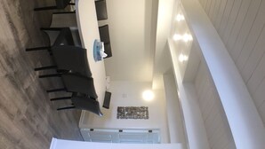 A modern dining area with a white table and black chairs, a tissue dispenser, and a decorative wall piece. - Ocean Colony 11, direct ocean front townhouse at 47th street (Ocean City)