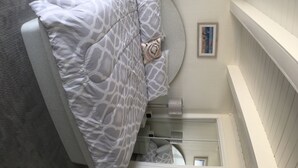 A bedroom with a bed, a round headboard, a framed picture on the wall, and a radiator. - Ocean Colony 11, direct ocean front townhouse at 47th street (Ocean City)