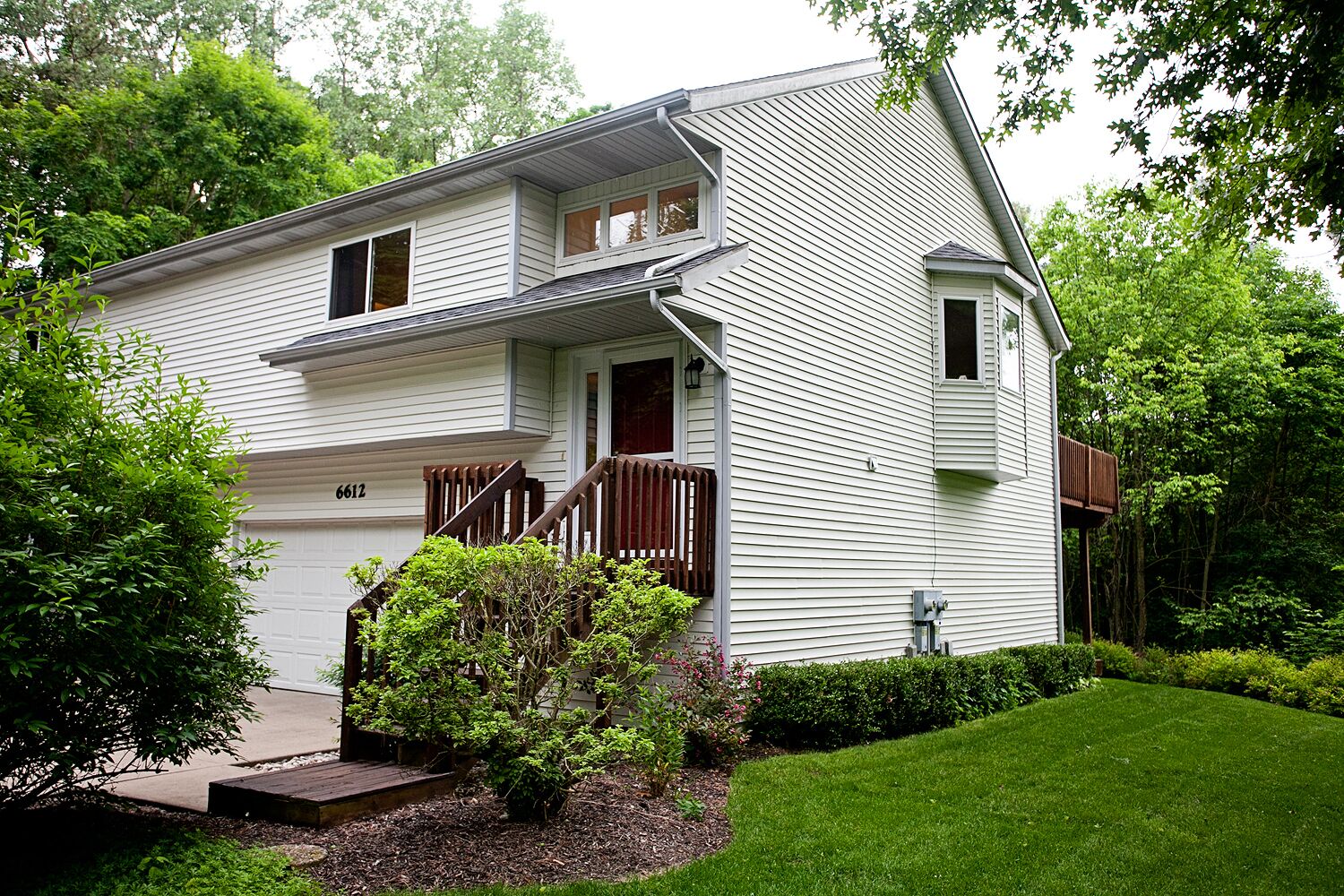 A two-story house with a front porch, a garage, and a well-maintained lawn.