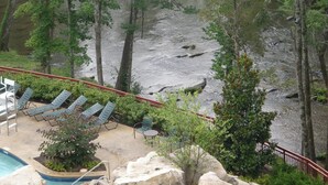 A pool area with lounge chairs and a view of a river.