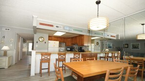 Een keuken met houten kastjes, een eettafel met stoelen en een keukeneiland.