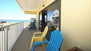 Een balkon met twee stoelen, een tafel en uitzicht op het strand en de oceaan.