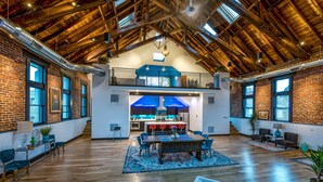 A spacious interior with a high ceiling, exposed wooden beams, and a central dining area with a table and chairs. - Luxurious, Converted Church Ideal for Large Groups near RiNo District, Sleeps 22 (Denver)