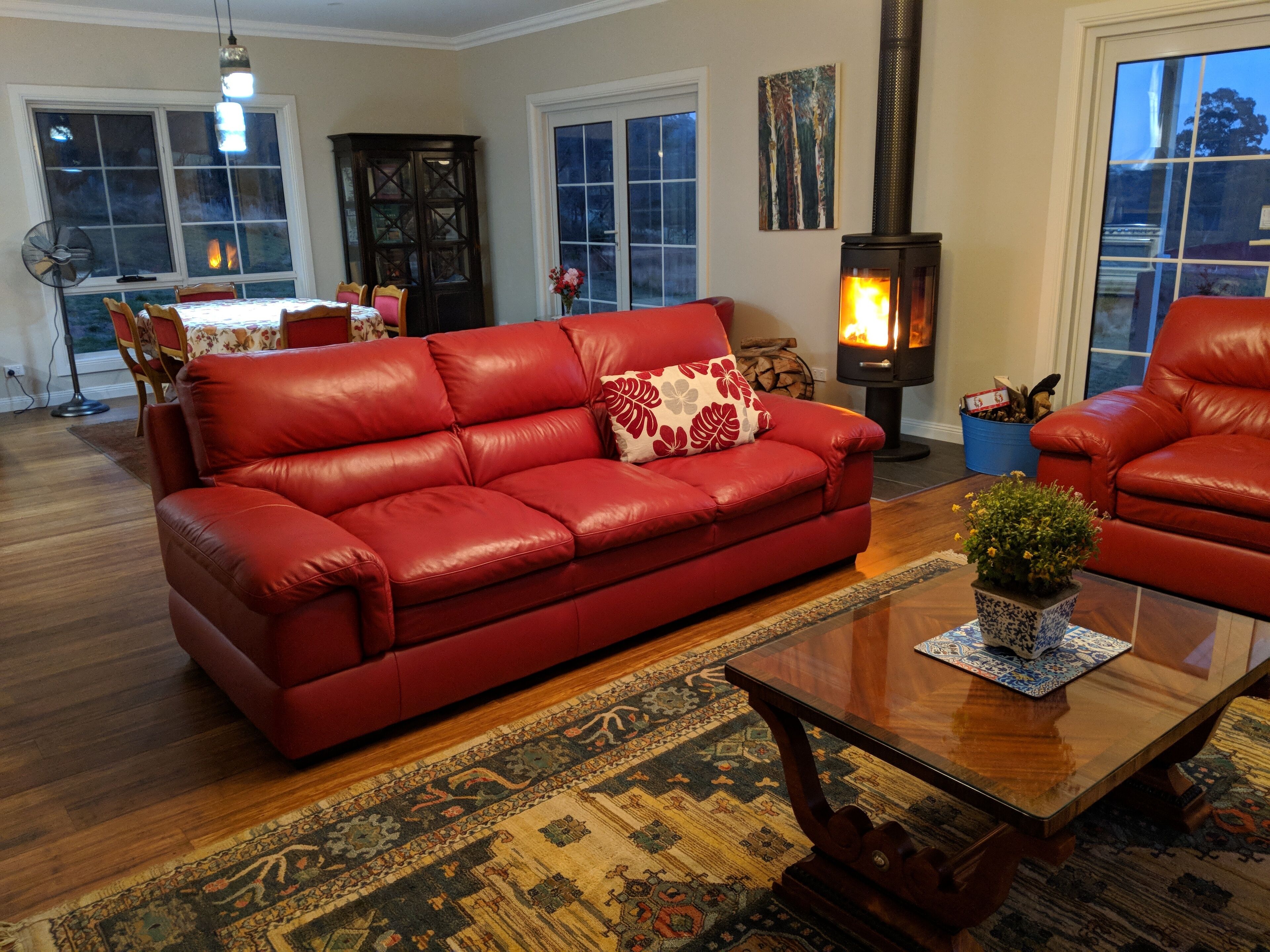 A living room with a red leather sofa, a wooden coffee table, and a large window.