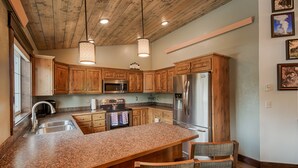 A kitchen with wooden cabinets, granite countertops, stainless steel appliances, and a large island with seating.