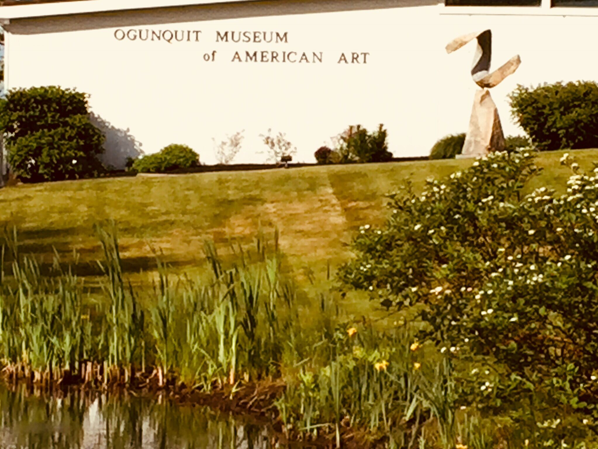 A sign for the Ogonquit Museum of American Art with a sculpture in the background.