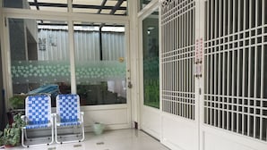 A covered outdoor seating area with two blue and white patterned chairs, a tiled floor, and a metal gate. - Guanshan Fukuda Homestay (Guanshan)