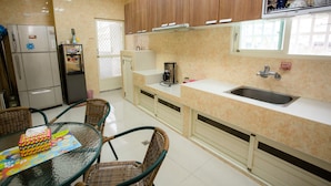 A kitchen with a refrigerator, coffee maker, and a dining area with chairs and a table. - Guanshan Fukuda Homestay (Guanshan)