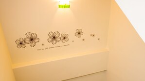 A staircase with a handrail, a wall with a light fixture, and a decorative floral pattern with a quote. - Guanshan Fukuda Homestay (Guanshan)