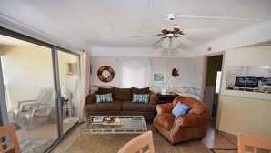 Un salon avec un canapé marron, une table basse en verre et un ventilateur de plafond.