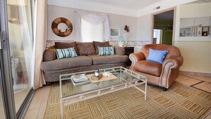 Un salon avec un canapé marron, une table basse en verre et un fauteuil en cuir marron.