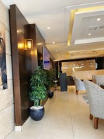 Un vestíbulo moderno con una recepción, zona de estar y una planta grande en maceta.