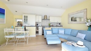 A modern kitchen with white cabinets, a central island, and a dining area with a glass table and chairs.