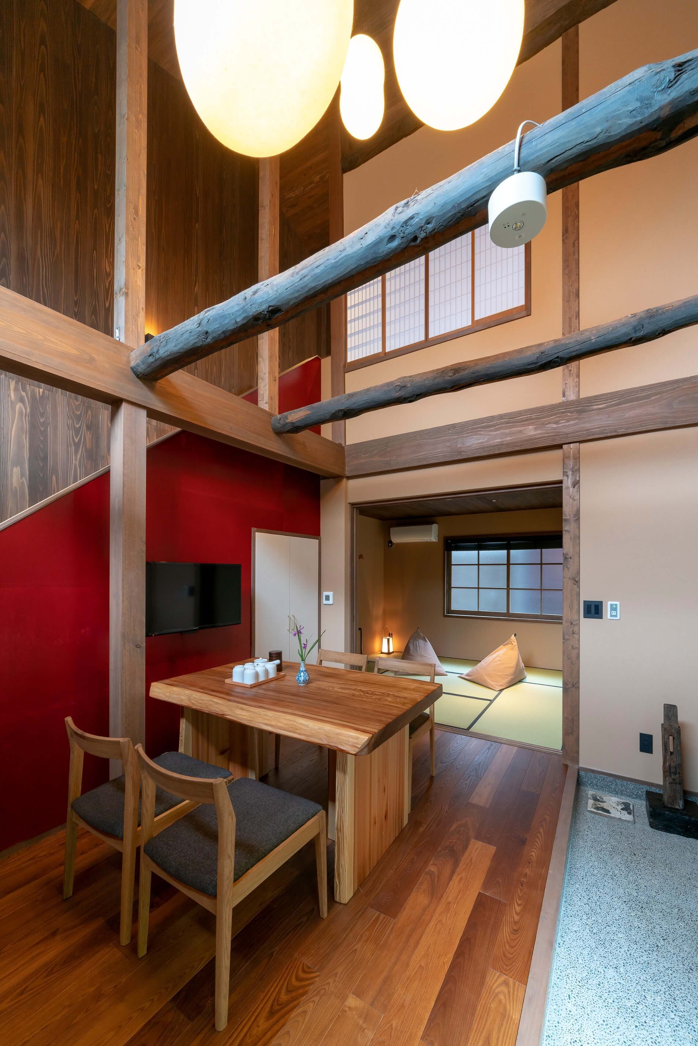 A traditional Japanese room with tatami flooring, a low wooden table, and a television mounted on the wall.