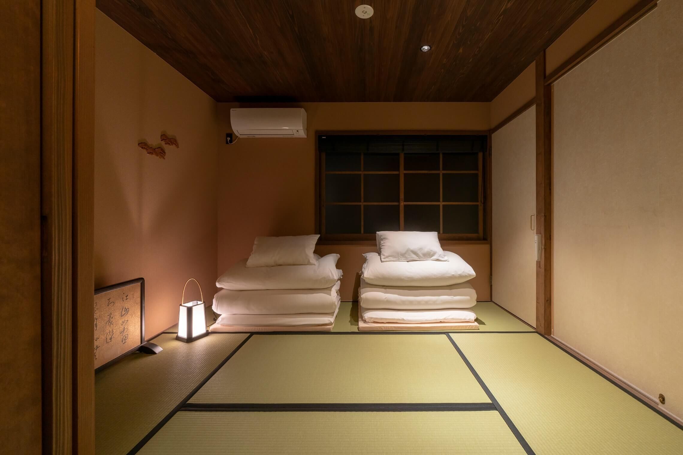 A traditional Japanese room with tatami flooring, a shoji screen door, and a futon bed setup.