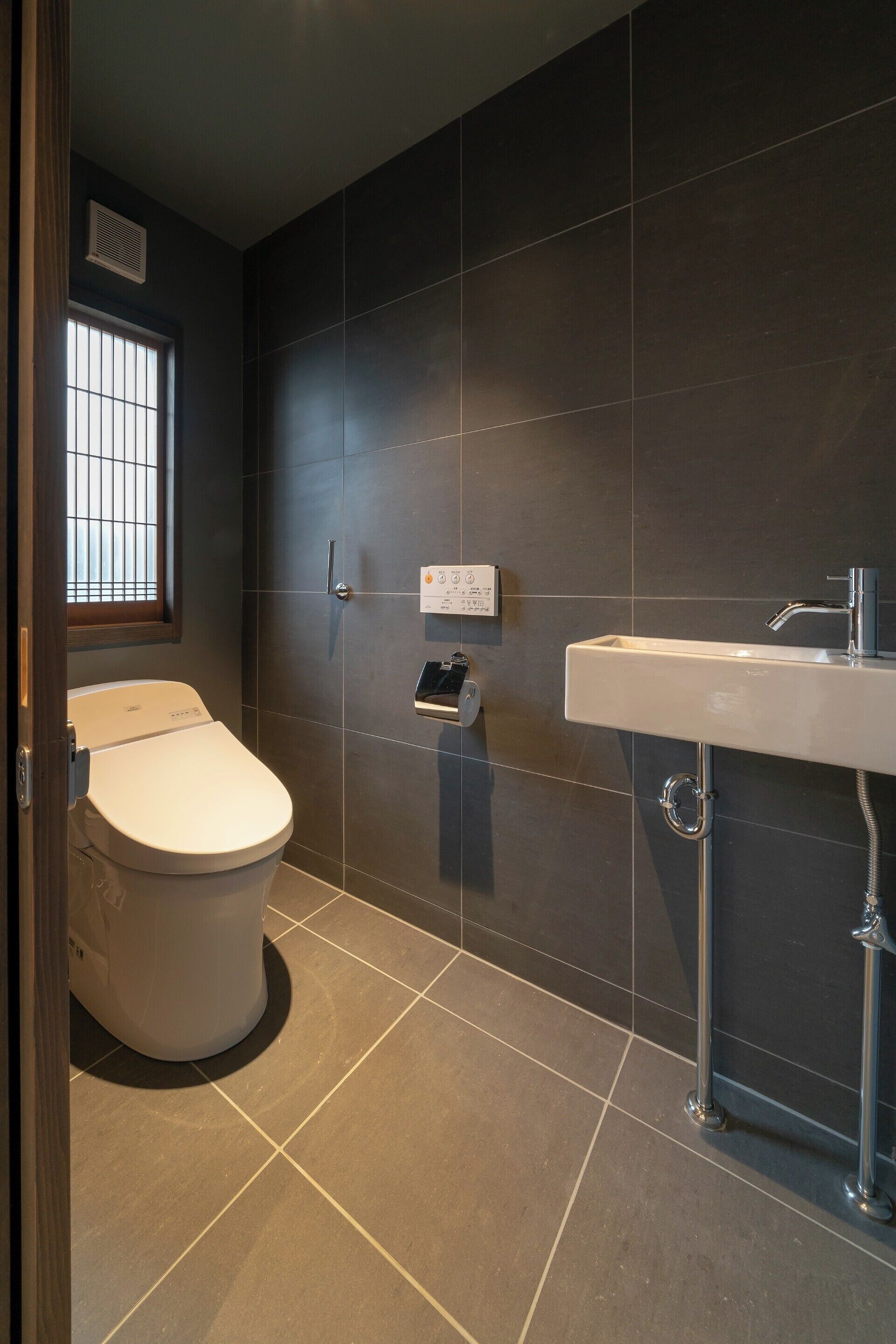 A modern bathroom with a toilet, a sink, and a window.