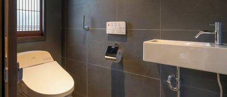 A modern bathroom with a toilet, a sink, and a window.