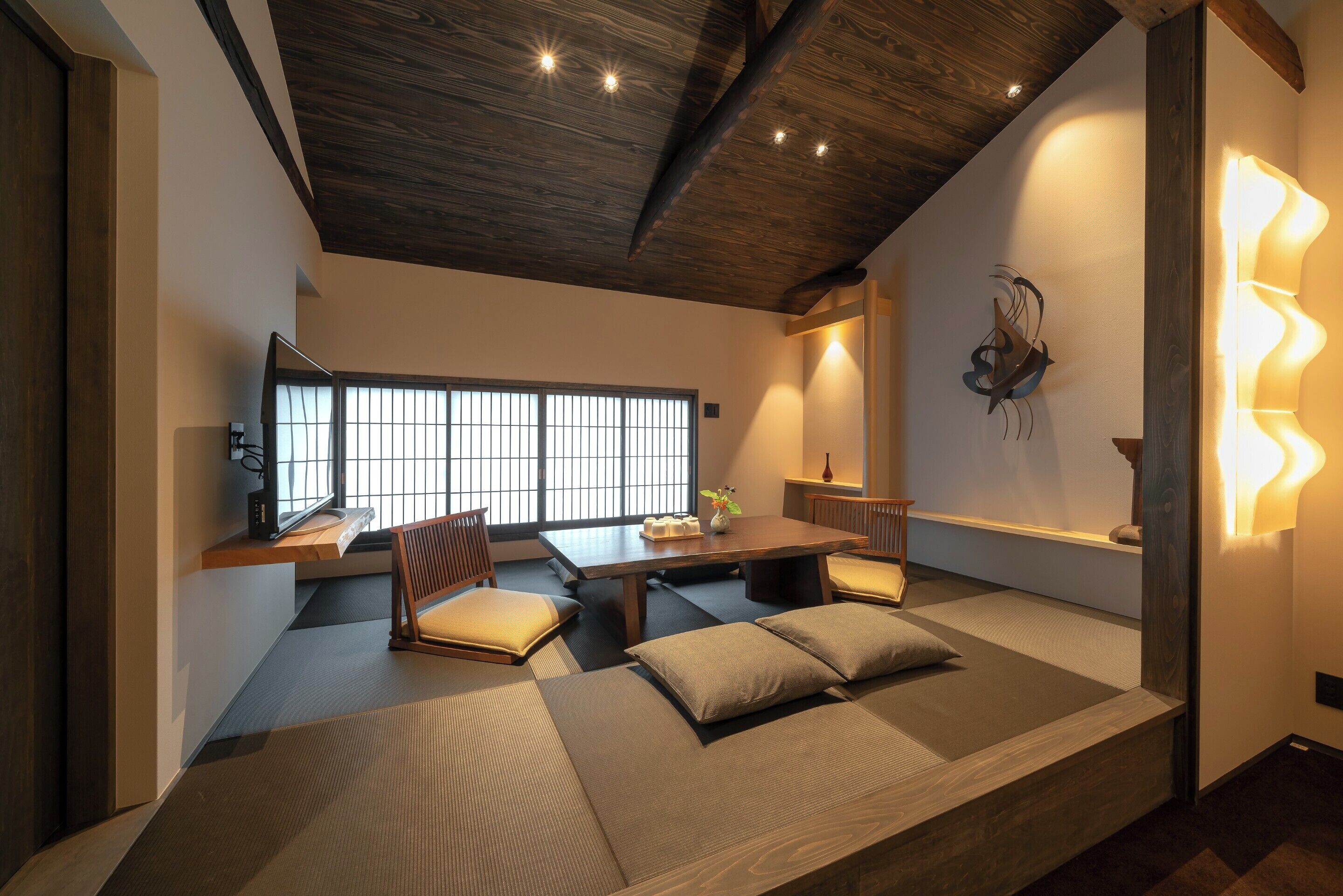 Una habitación al estilo japonés tradicional con suelo de tatami, una mesa de madera baja y una zona de estar acolchada.