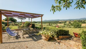 Zona d'estar a l'aire lliure amb una pérgola, gandules i un banc de fusta.