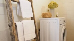 A laundry area with a wooden ladder, a washing machine, and a basket on a white cabinet. - I Cortivi 2   Montebaldo (Costermano)