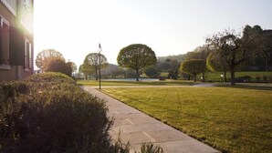 A pathway leading through a well-maintained grassy area with trees and a building on the left. - I Cortivi 2   Montebaldo (Costermano)
