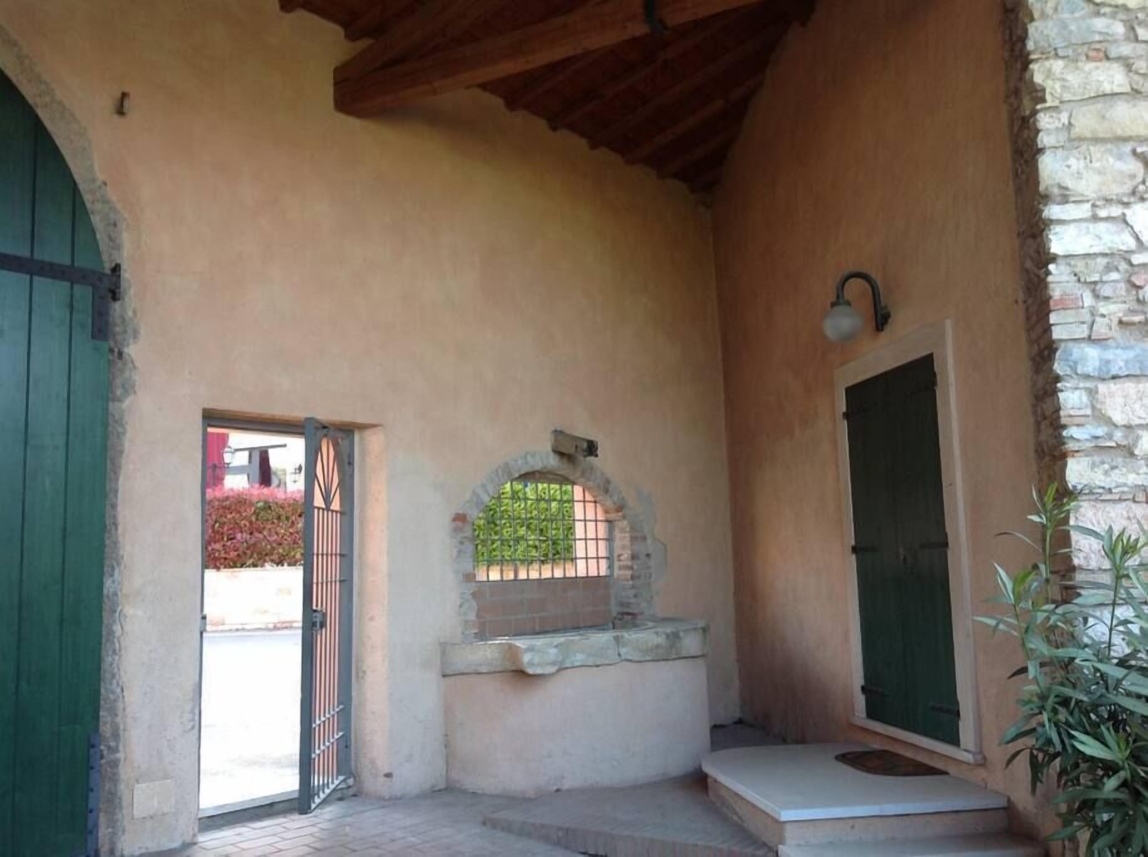 A covered outdoor area with a stone wall, a metal gate, and a door.