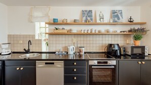 A modern kitchen with black cabinets, a built-in oven, and a coffee maker. - Beautiful shoreline holiday home with private mooring, Njivice, Montenegro (Njivice)