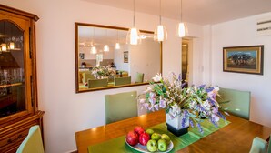 A dining area with a wooden table, chairs, a mirror, and a vase with flowers. - Beautiful shoreline holiday home with private mooring, Njivice, Montenegro (Njivice)