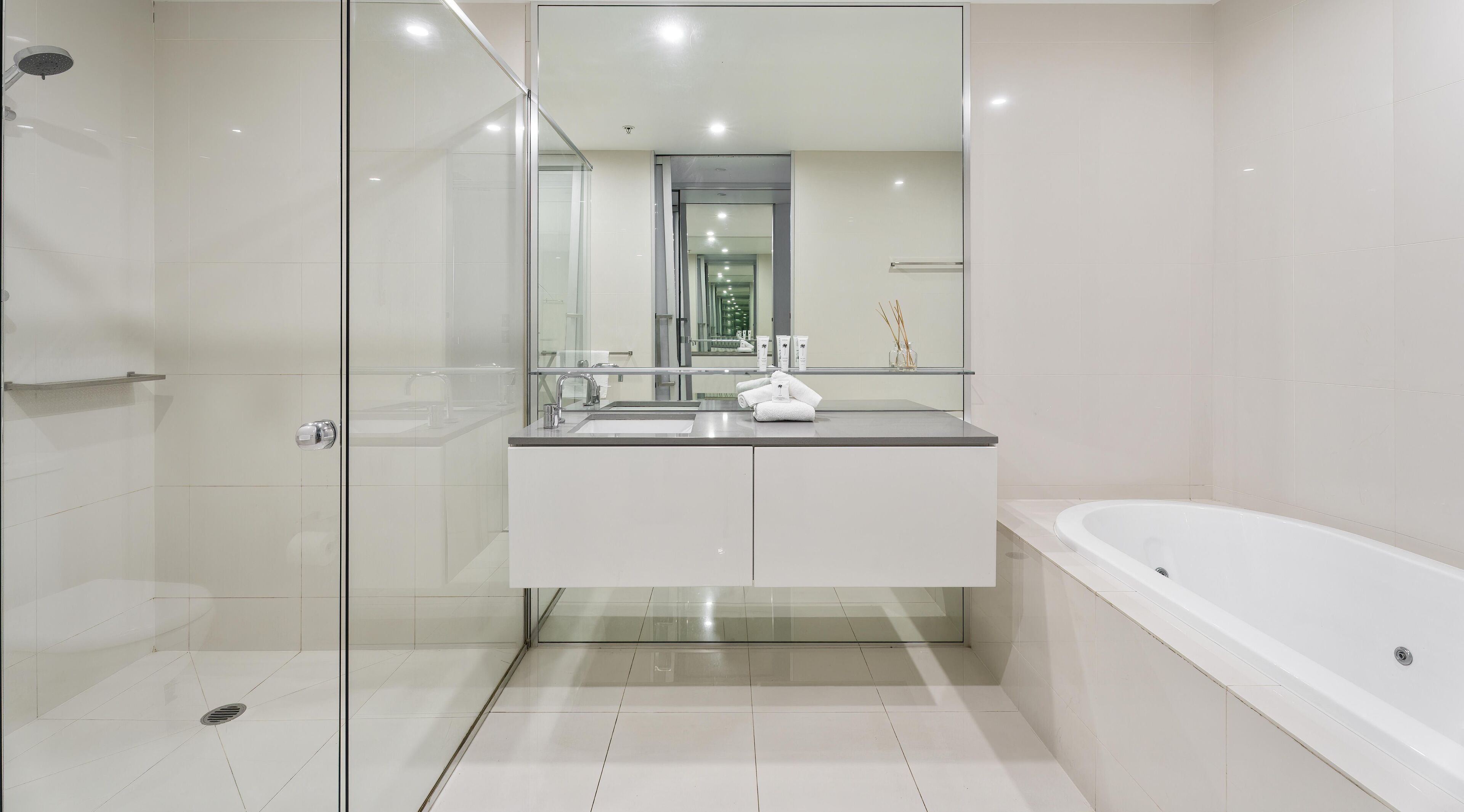 A modern bathroom with a glass shower enclosure, a white sink with a mirror above, and a standalone bathtub.
