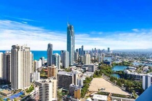 A cityscape with high-rise buildings, a prominent skyscraper, and a body of water in the background.