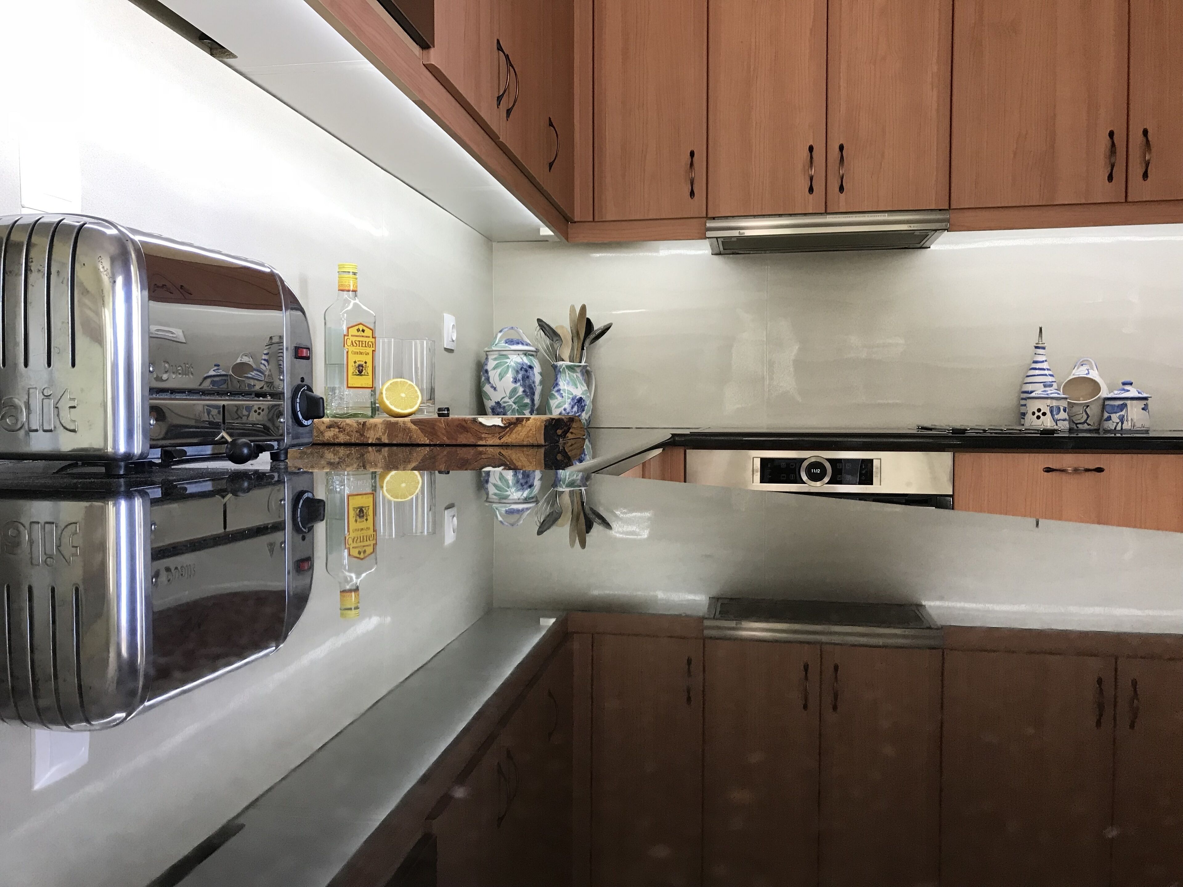 A kitchen with a stainless steel range, wooden cabinets, and a reflective countertop.
