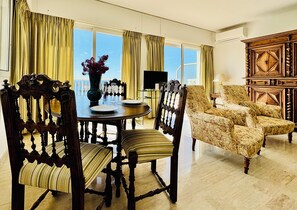 A dining area with a round table, chairs, a vase with flowers, and a television.