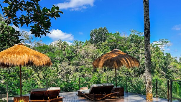 A poolside area with lounge chairs and thatched umbrellas, surrounded by lush greenery. - Villa Kalisha - Romantic Honeymoon or Family Getaway in Ubud (Tegallalang)