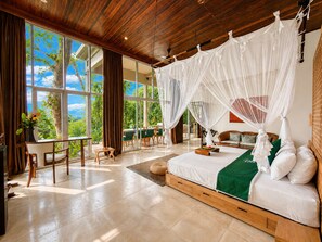 A spacious room with a large bed, a dining area, and a view of the outdoors.