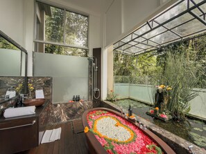A bathroom with a large bathtub, a shower, a sink, and a mirror.