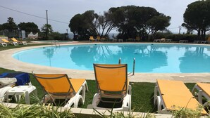 A swimming pool with lounge chairs and a grassy area in the foreground. - Apartment in resort 3* at 1mn to the beach - Algarve (Porches)