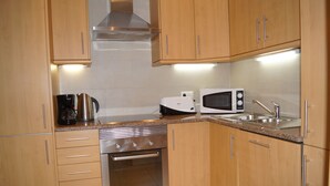 A kitchen with wooden cabinets, stainless steel appliances, a coffee maker, a microwave, and a sink. - Apartment in resort 3* at 1mn to the beach - Algarve (Porches)