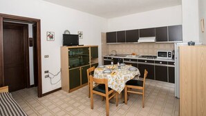 A compact kitchen with a dining table, chairs, and basic appliances.