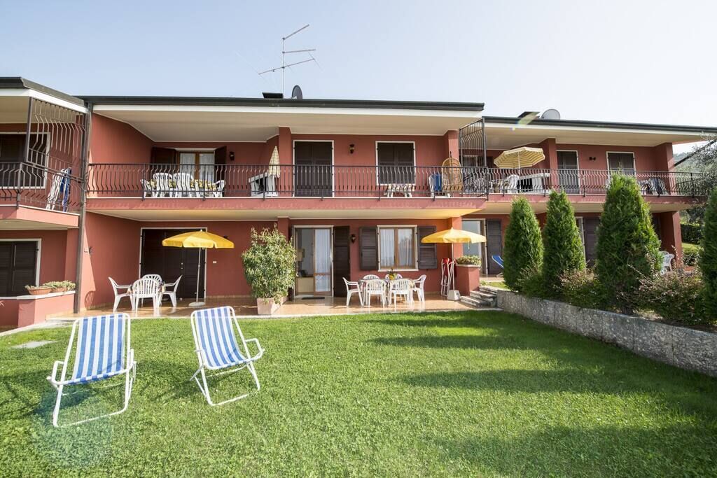 A two-story building with balconies, outdoor seating, and a well-maintained lawn.