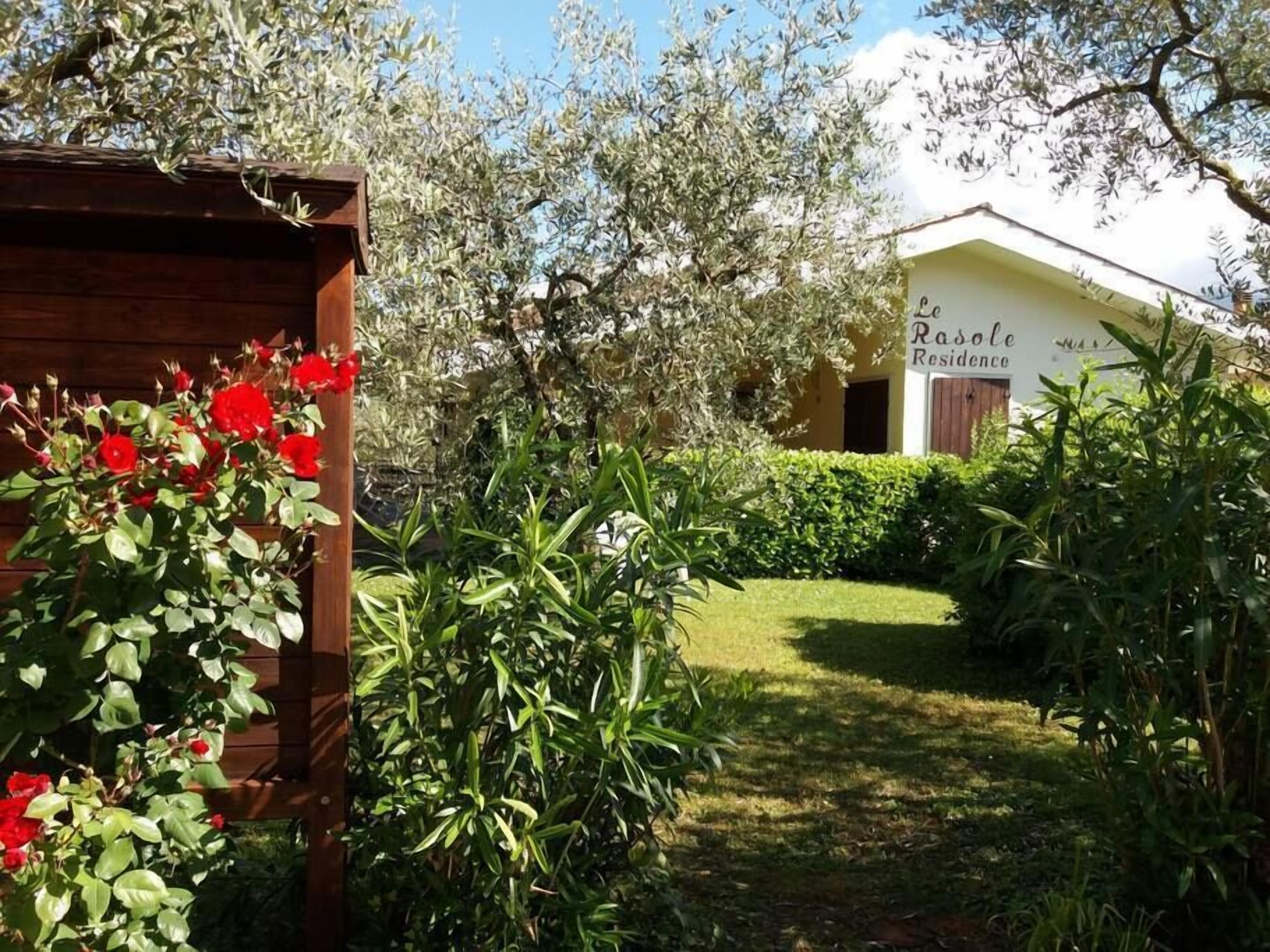 A garden with a wooden structure and red flowers, leading to a building labeled "La Roselle Residence".