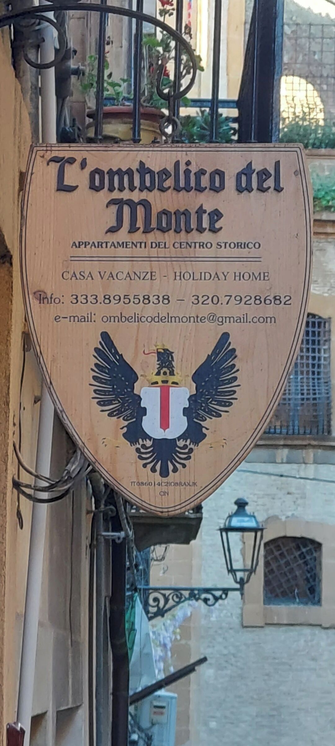 A wooden sign with the text 'L'ombrello del Monte' and contact information for a holiday home.