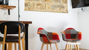 Ein modernes Zimmer mit einem Holzesstisch, zwei Stühlen und einem an der Wand montierten Fernseher.